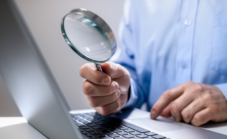 Image of a magnifying glass and laptop